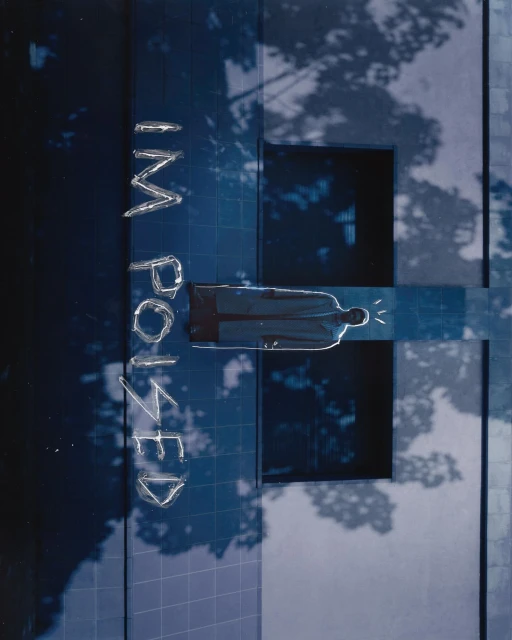 Abstract blue-toned shot featuring a person's silhouette on a geometric grid, architectural details, tree shadows, and bold text.