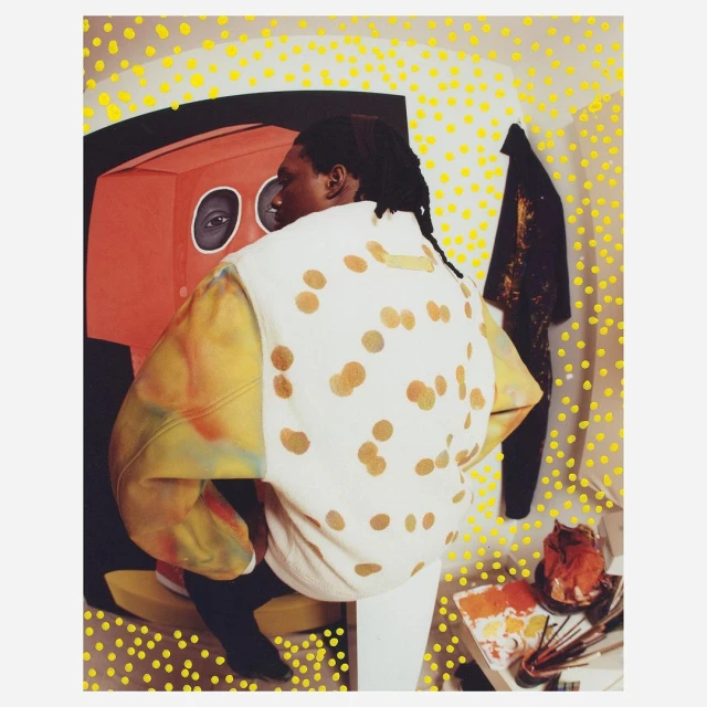 Person from behind wearing a white polka-dot top, standing in front of an orange art piece and white wall dotted with yellow.