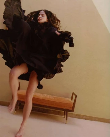 Woman in dark flowing dress leaping mid-air indoors in a portrait by photographer Elliot James Kennedy
