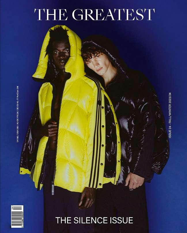 Fashion magazine cover featuring two models in hooded puffer jackets, one yellow and one black, against a blue background.