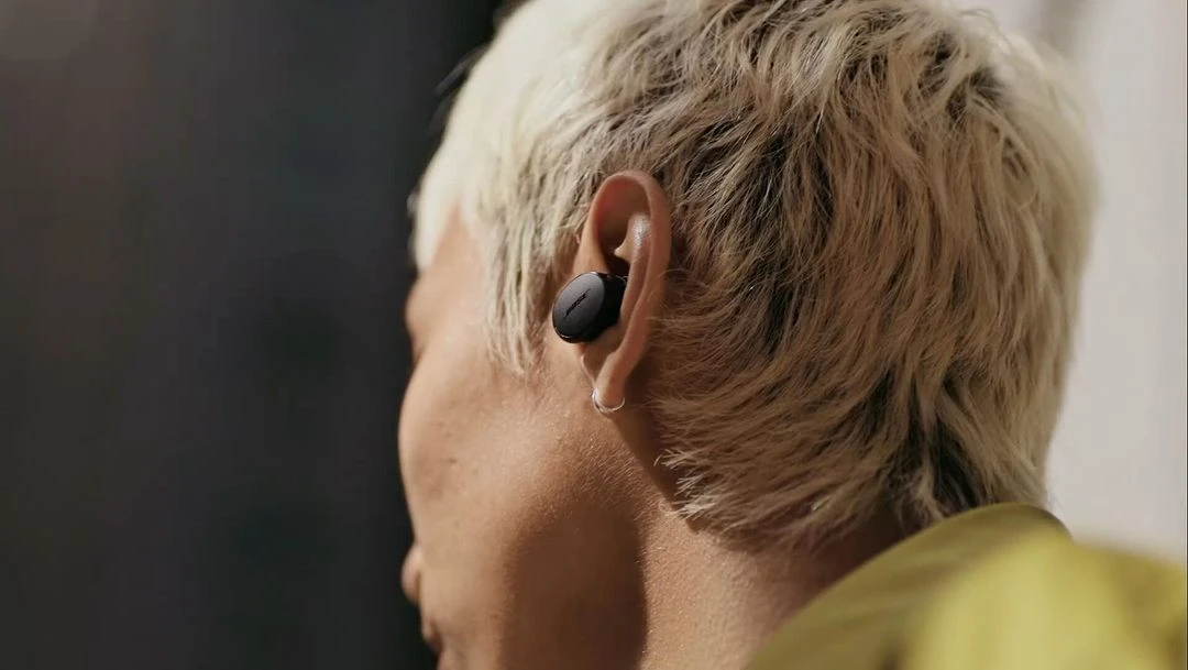 Close-up of an adult's ear with a black wireless earbud, highlighting personal audio technology and modern wearable design.