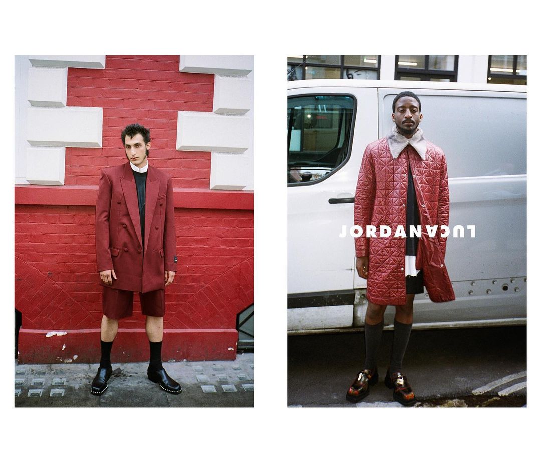 Two stylish men in coats stand against urban backdrops: one against a brick wall, the other near a white van, showcasing modern fashion.