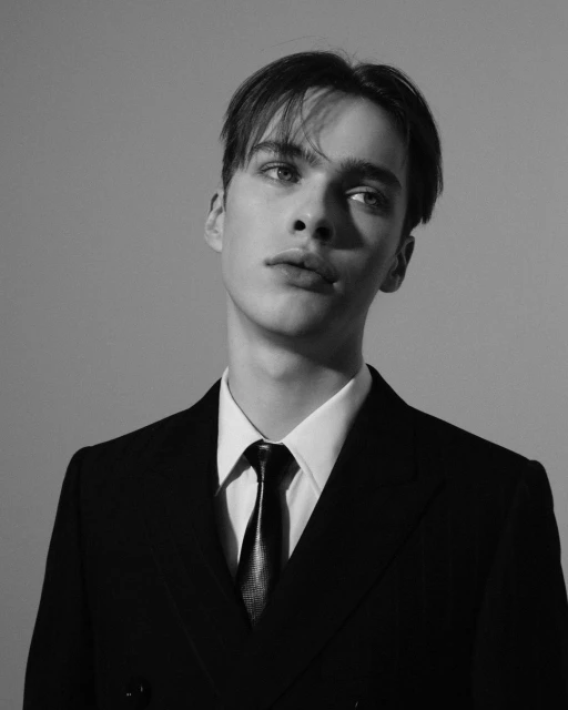 Black and white portrait of an adult male wearing a suit and tie in a photo studio with a neutral background, professional attire.