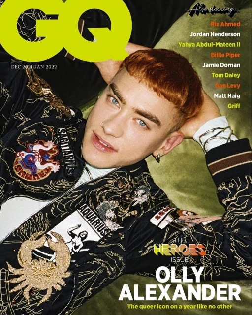 Magazine cover featuring Olly Alexander with 'GQ' logo. He wears a Zodiac-themed jacket against a green backdrop with other celebrity names.