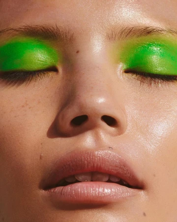 Close-up portrait of a woman with vibrant green eyeshadow and glossy lips shot by Ellyse Anderson in London