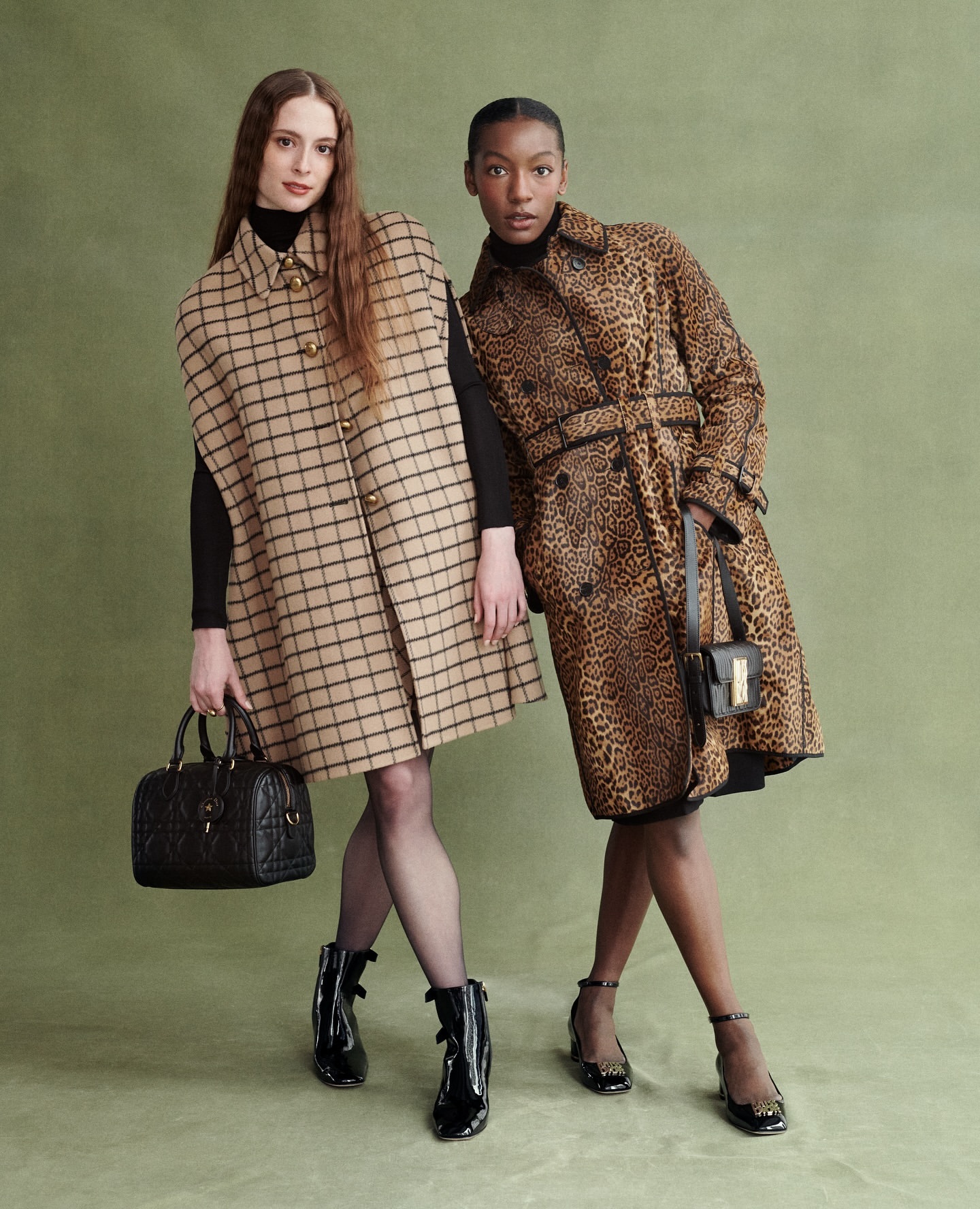 Two fashion models in coats, one in tan plaid and the other in leopard print, stand against a green backdrop, accessorized with purses and ankle boots.