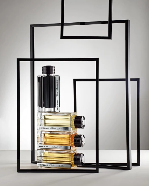 Still life shot of Montblanc men's cologne bottles stacked on each other within decorative black square frames against a gradient background.