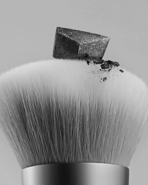 Close-up of a makeup brush with a dark glitter eyeshadow cube on top, set against a neutral background in a studio shot.