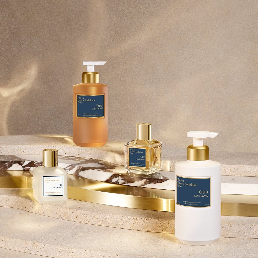 Product shot featuring a collection of Maison Francis Kurkdjian Oud satin mood scented products: bottles, dispensers in a studio setting.