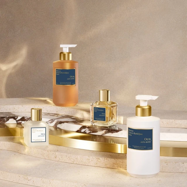 Product shot featuring a collection of Maison Francis Kurkdjian Oud satin mood scented products: bottles, dispensers in a studio setting.