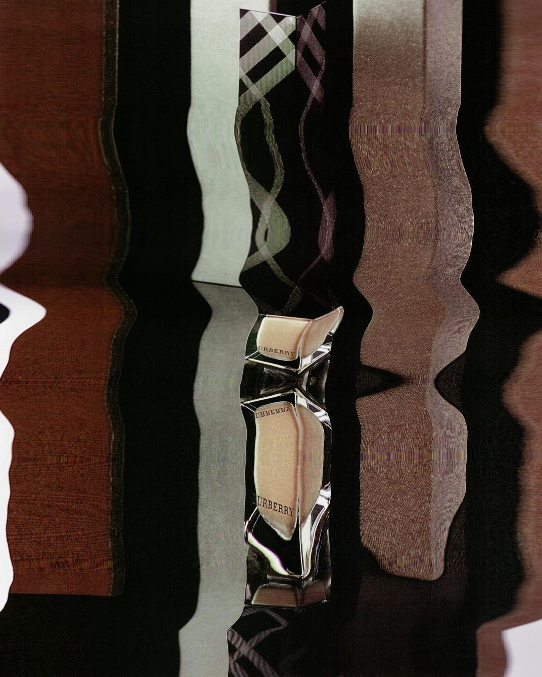 Crystal Burberry perfume bottle with beige liquid stands out against textured vertical panels in brown, gray, and black tones.
