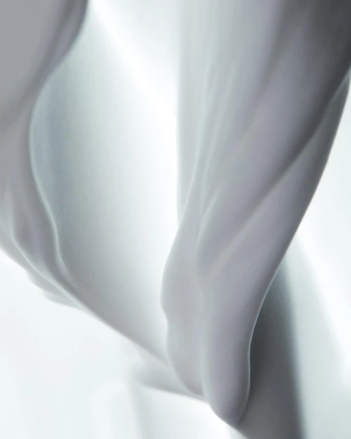 Abstract close-up of flowing white fabric with soft lighting creating depth and smooth textures, suitable for beauty and fashion themes.