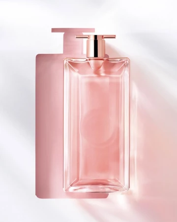 Close-up studio shot of a clear glass perfume bottle with a pink liquid inside, casting a shadow on a white background.