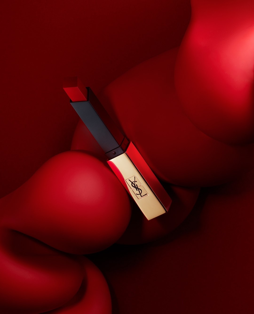 YSL lipstick tube in gold and black against a blurred red background. Beauty shot for cosmetics with a focus on color and style.