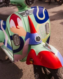 Close-up of a pastel green scooter painted with abstract shapes in red, blue, and purple by illustrator Elsa Martino in Paris.