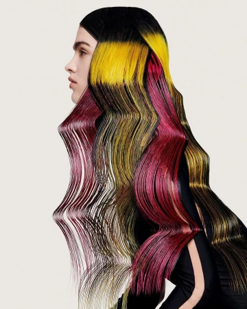 Creative portrait of a woman with long, stylized hair that is dyed in black, yellow, and red hues on an off-white background.