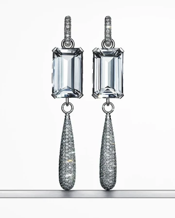Elegant dangle earrings featuring emerald-cut gemstones and pave diamonds set in silver-tone metal, displayed against a gradient white backdrop.