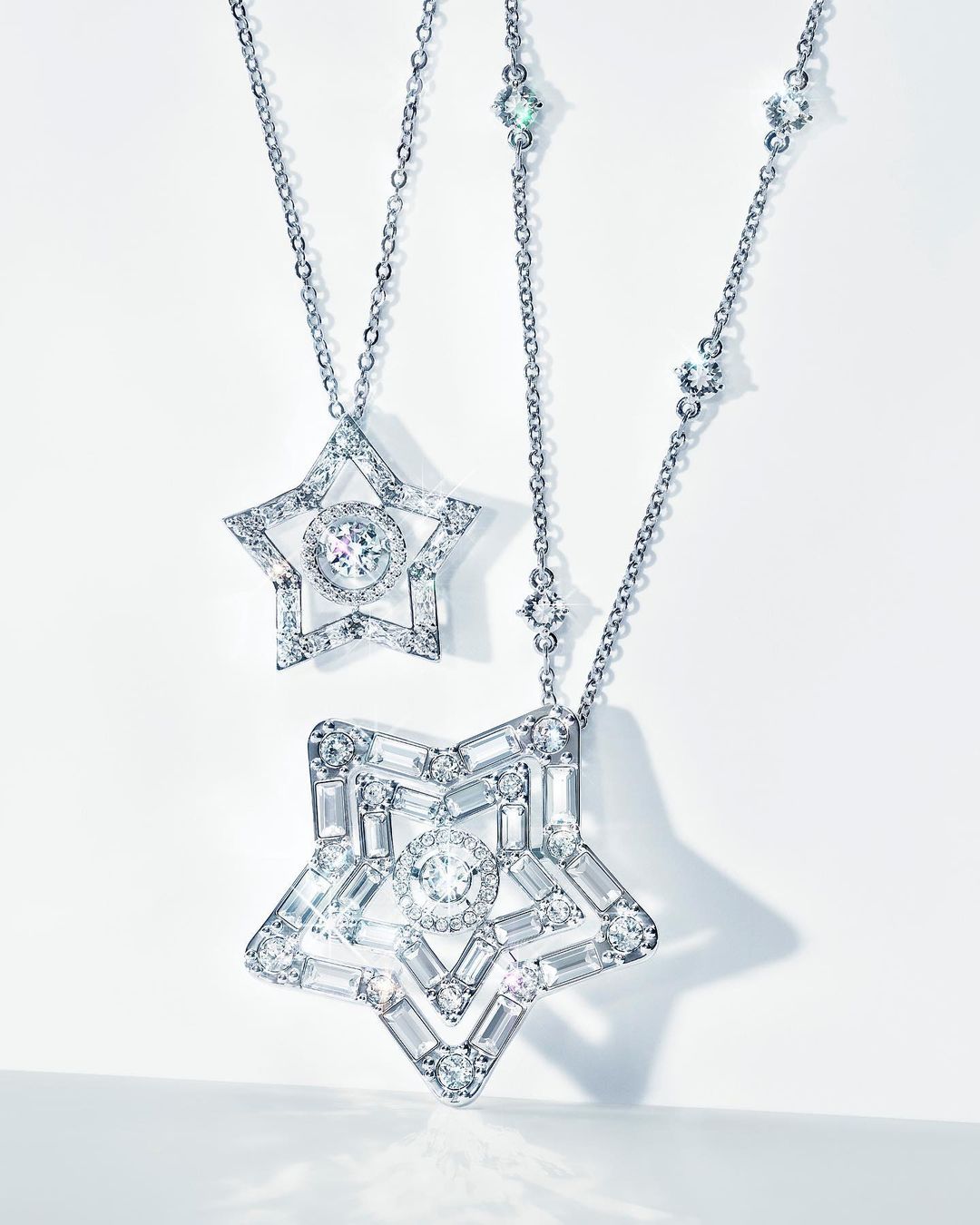 Two elegant necklaces with star-shaped pendants encrusted with diamonds, displayed on a clean white background, showcasing luxury jewelry.