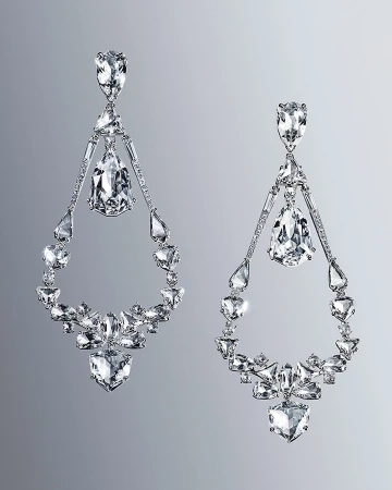 Elegant chandelier earrings sparkle against a gray background. Statement jewelry features clear gemstones in geometric and teardrop shapes.