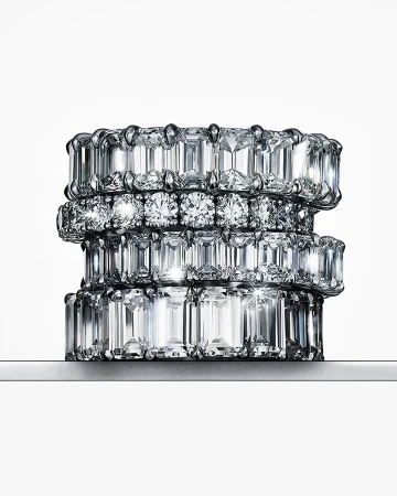 Stack of four eternity rings featuring clear diamonds in varying cuts on a white background, jewellery photography.