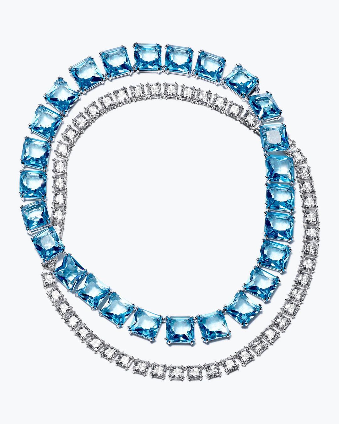 Elegant jewelry arrangement on a white background: A strand of square-cut aquamarine gems and a tennis bracelet create a luxurious display.