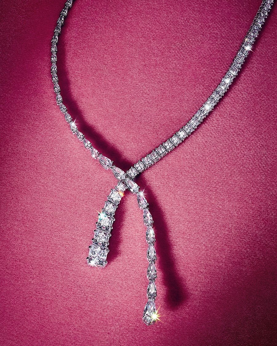 Sparkling diamond necklace displayed on a textured pink surface, showcasing jewelry design and luxury fashion accessory.