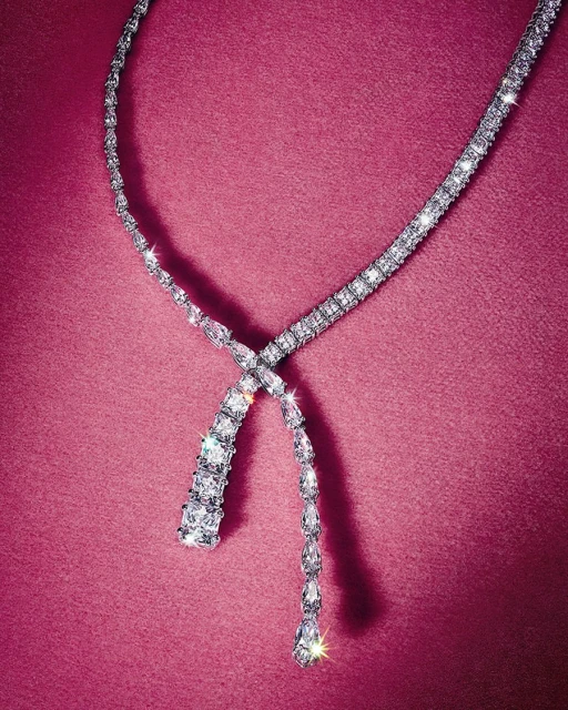 Sparkling diamond necklace displayed on a textured pink surface, showcasing jewelry design and luxury fashion accessory.
