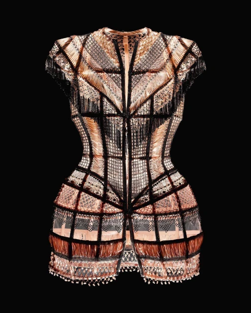 Intricate couture dress with copper and black fringe details against a black background, highlighting fashion design and craftsmanship.