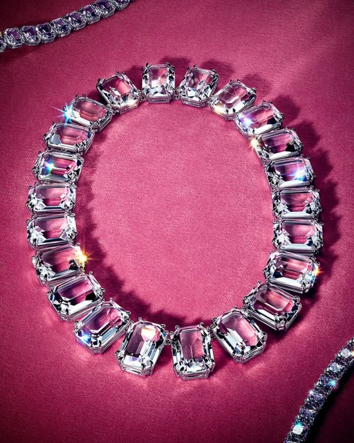 Necklace featuring large clear gemstones in silver settings on a textured magenta background with sparkling accents. Jewelry.
