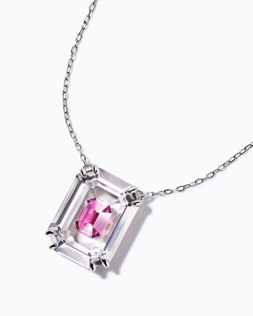 Elegant necklace featuring a silver chain and a geometric pendant with a clear stone and a smaller pink stone inside, studio lighting.