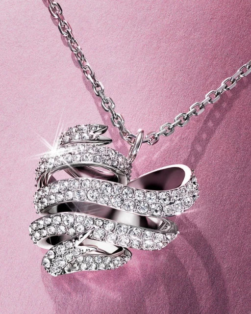 Sparkling crystal pendant necklace with a silver chain and a pink backdrop. Elegant jewelry design for fashion or special occasions.