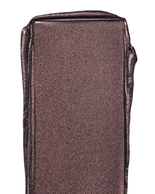 Close-up of shimmering bronze-colored makeup swatch, capturing its reflective texture and rich pigment on a white backdrop.