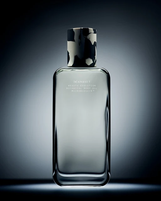 Studio shot of a rectangular glass bottle with patterned black and white cap against a dark blue gradient background with studio lighting.