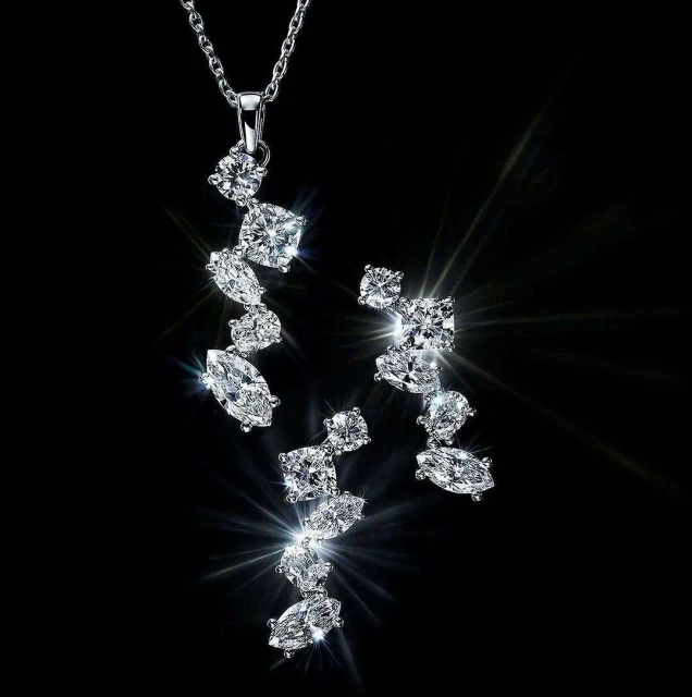 Elegant jewelry set on a black background showcasing a silver necklace and matching earrings adorned with sparkling, clear gemstones.