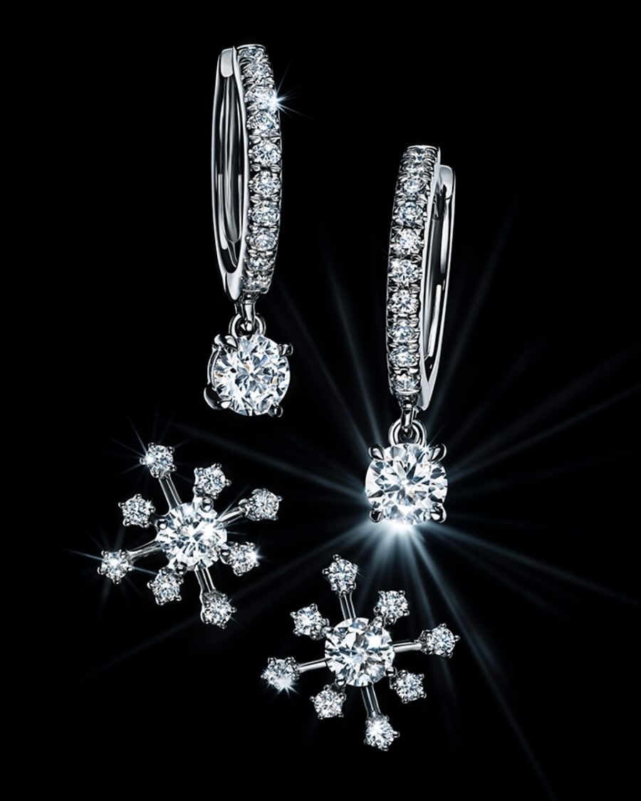 Elegant diamond earrings and snowflake pendants sparkle against a dark backdrop, showcasing fine jewelry and intricate design.