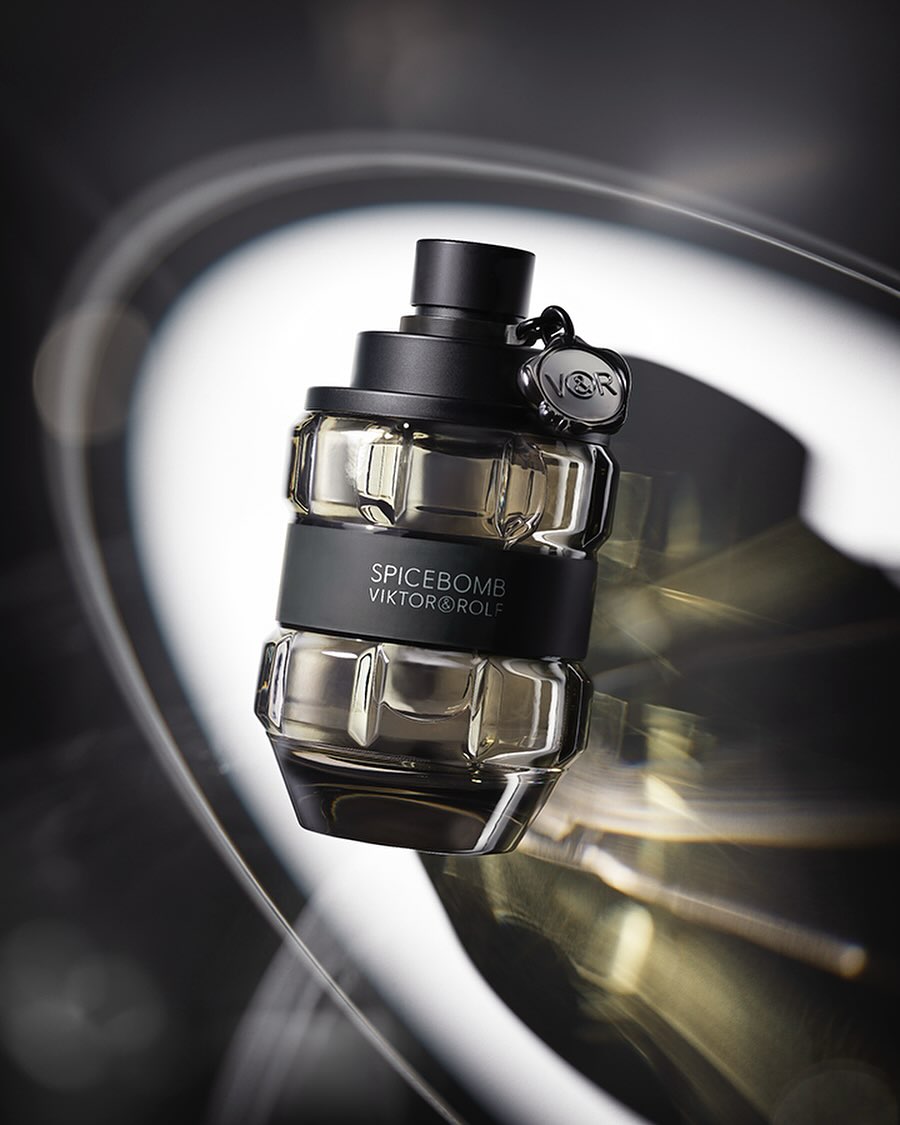 Viktor & Rolf Spicebomb bottle on a reflective surface with dramatic lighting creating abstract light trails in the background.