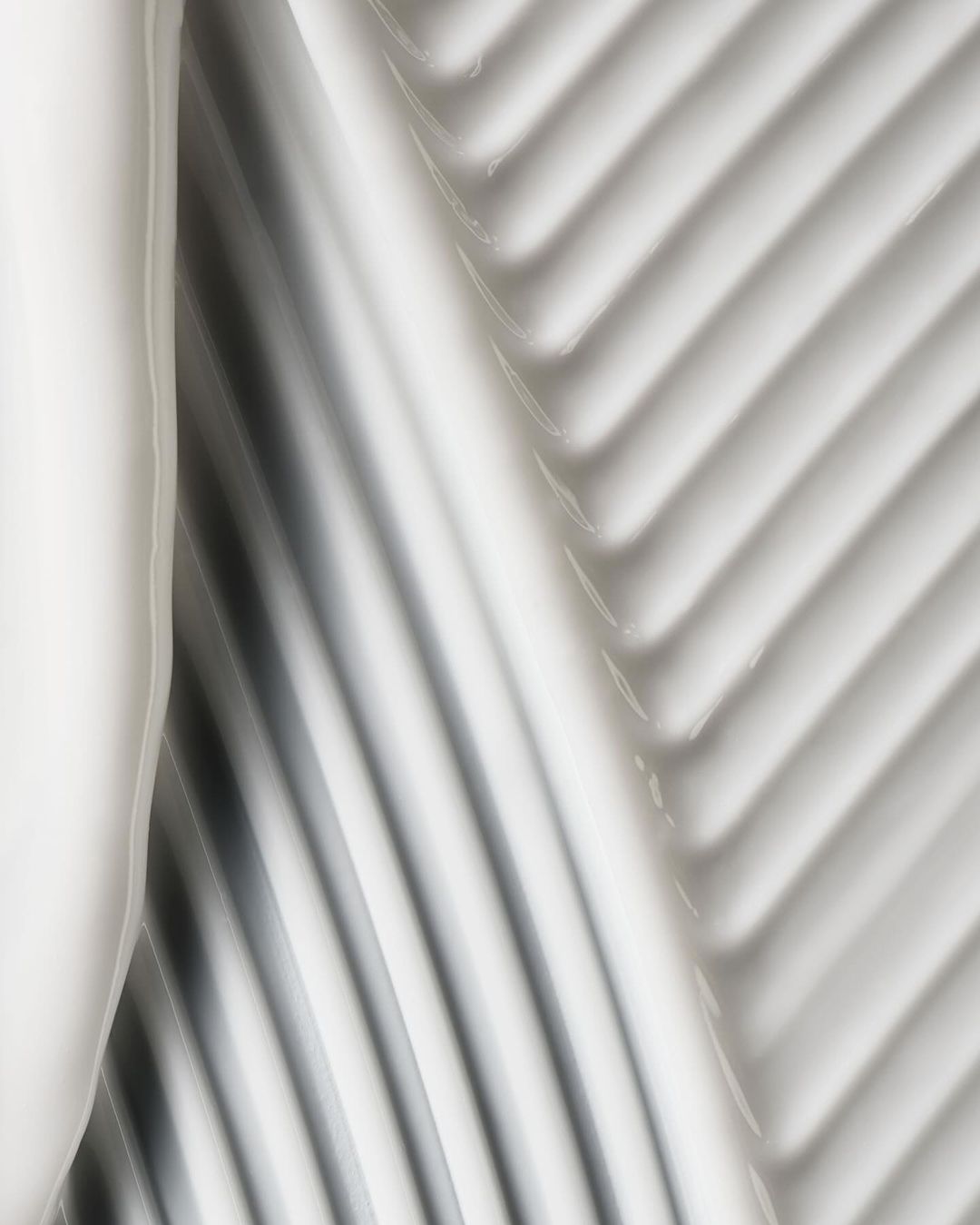 Abstract close-up of thick, glossy white cream with diagonal ridged texture, neutral lighting, ideal for beauty product marketing.
