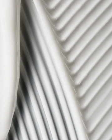 Abstract close-up of thick, glossy white cream with diagonal ridged texture, neutral lighting, ideal for beauty product marketing.