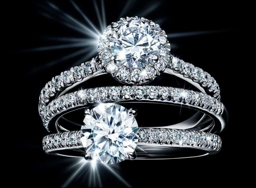 Close-up studio shot of three diamond rings. Focus on the large center diamonds with smaller diamonds surrounding them and the band.
