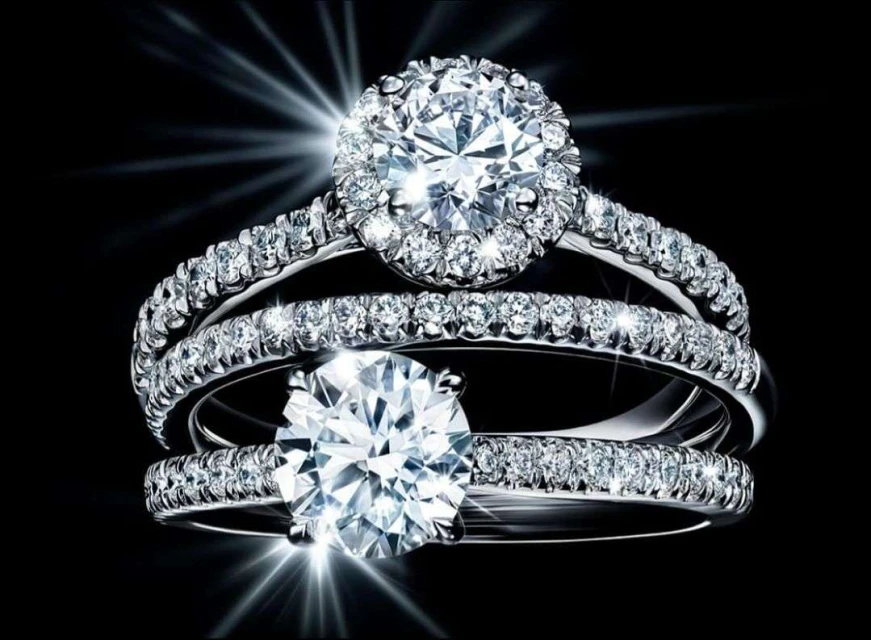 Close-up studio shot of three diamond rings. Focus on the large center diamonds with smaller diamonds surrounding them and the band.