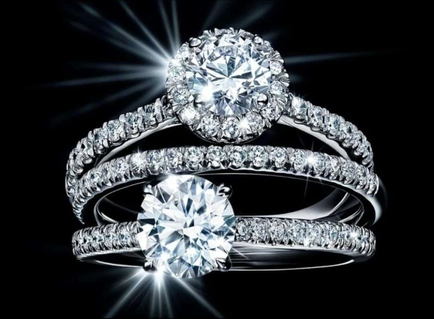 Close-up studio shot of three diamond rings. Focus on the large center diamonds with smaller diamonds surrounding them and the band.