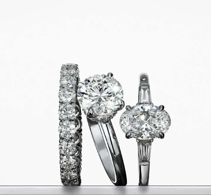 Three diamond rings are displayed against a gradient white background, showcasing sparkle and craftsmanship in a clean, elegant composition.