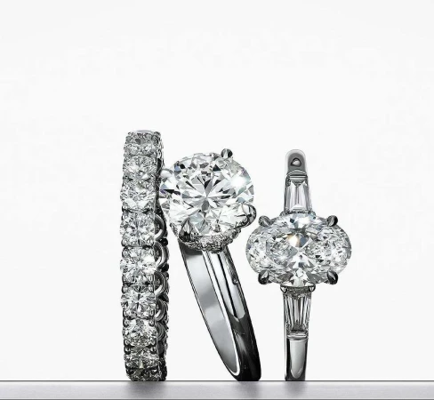 Three diamond rings are displayed against a gradient white background, showcasing sparkle and craftsmanship in a clean, elegant composition.