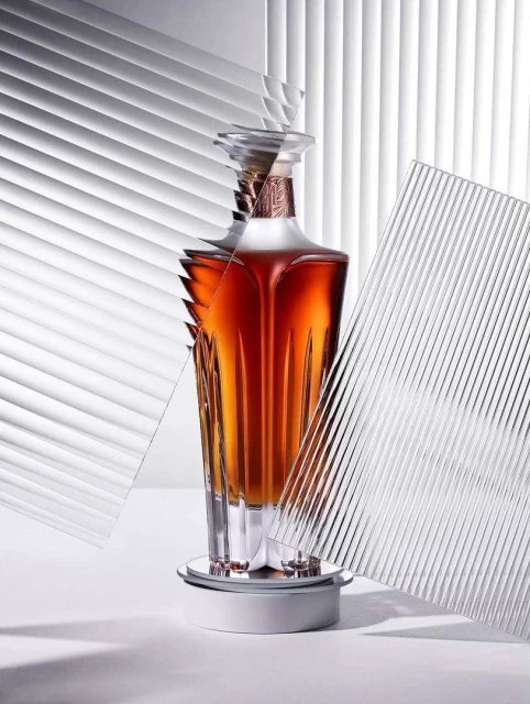 Elegant liquor bottle on a rotating platform, featuring clear textured glass panels and soft studio lighting against a white backdrop.