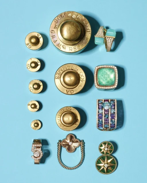 Overhead studio shot of antique brass weights and assorted gemstone rings on a light blue background. Jewellery and antique weights.