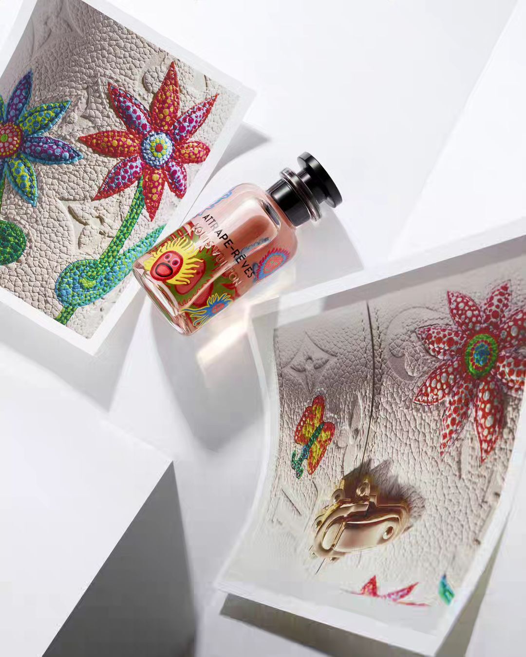 Close-up of a Louis Vuitton fragrance bottle surrounded by artwork featuring colorful floral designs on a white surface, studio setting.