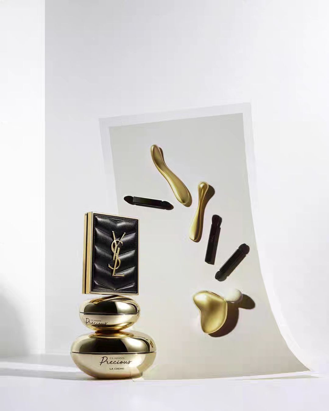 Yves Saint Laurent skincare and makeup products arranged in studio setting with cosmetic applicators, gold accents, and luxury branding.