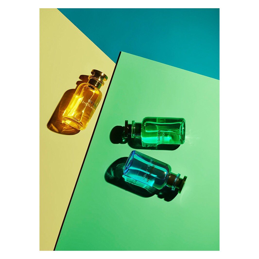 Three colorful perfume bottles are arranged on a vibrant background, featuring yellow, green, and blue sections, creating a modern design.