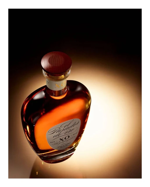 Elegant, aged rum in a stylish glass bottle with a wooden cap, set against a gradient light background in a close-up shot.