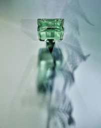 Green perfume bottle casting a long shadow with botanical patterns on a textured light background.